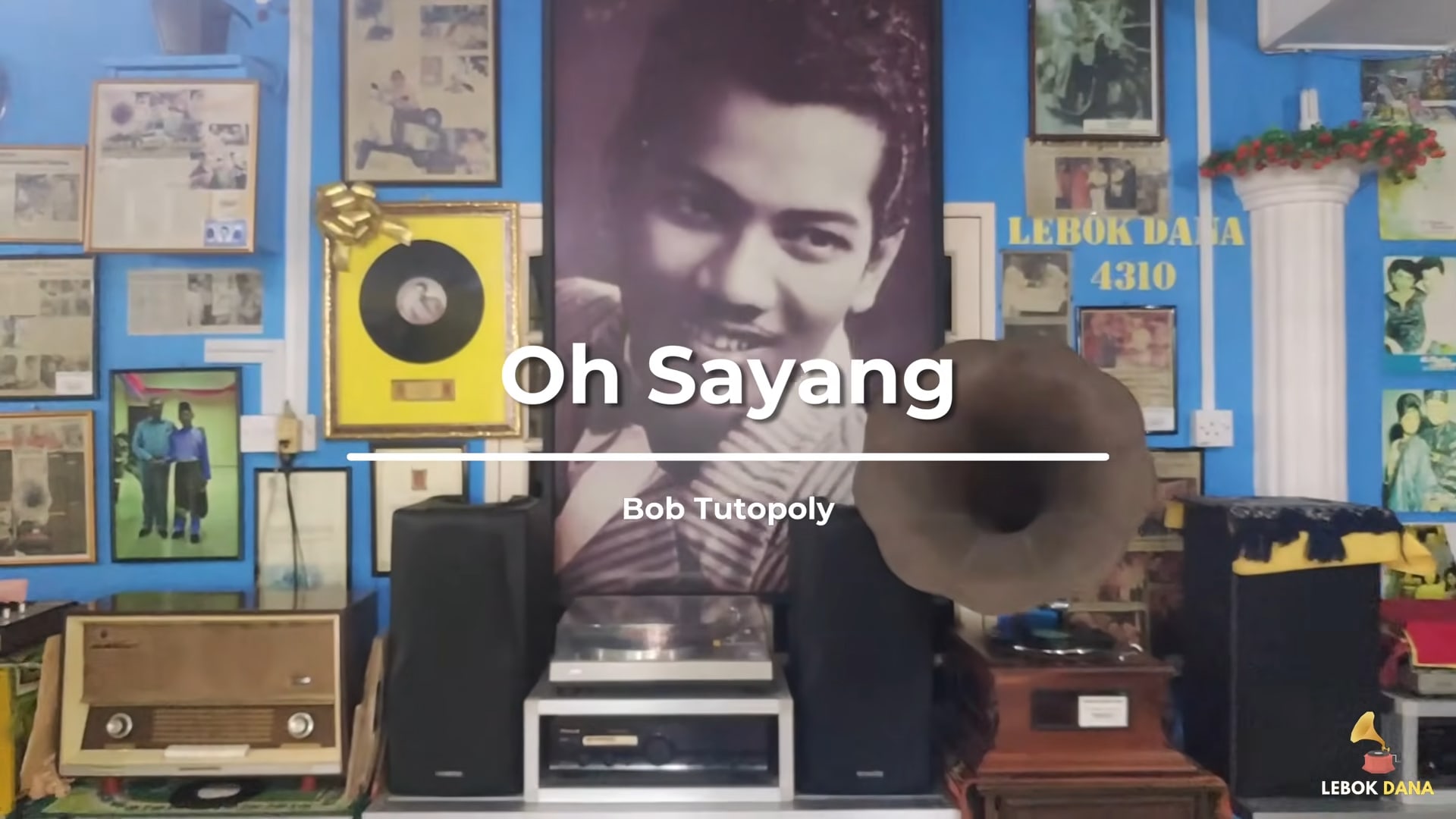 Kad tajuk video Oh Sayang nyanyian Bob Tutupoly, berlatarkan potret P. Ramlee, pemain piring hitam dan gramofon di Galeri Lebok Dana