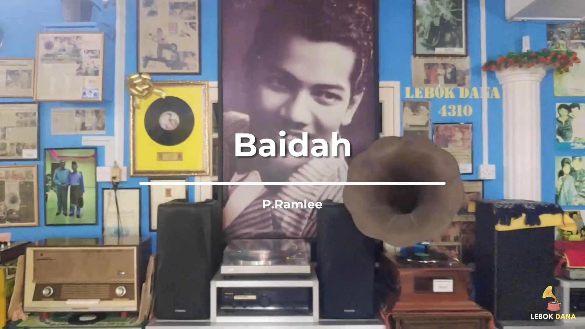 Kad tajuk video Baidah nyanyian P. Ramlee, dengan potret besar P. Ramlee, piring hitam berbingkai dan gramofon di dinding Galeri Lebok Dana